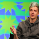 A man with fading, blue hair in a dark gray hoodie.